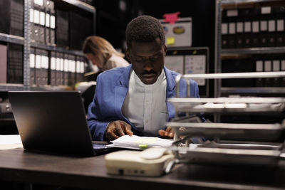 Portrait of young man using laptop at office