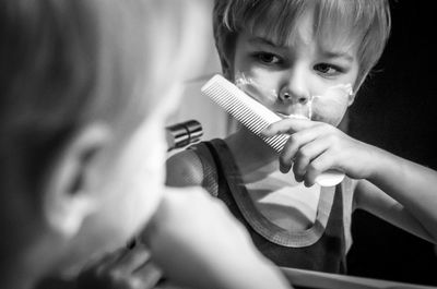 Reflection of boy holding hairbrush in mirror