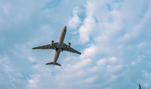 Directly below shot of airplane flying in cloudy sky