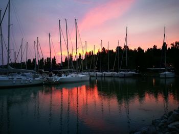 Boats moored at harbor against sky during sunset