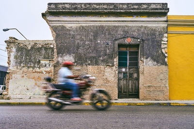 People riding motorcycle on road against building in city