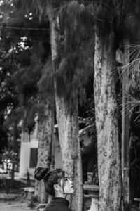 Woman standing by tree in forest