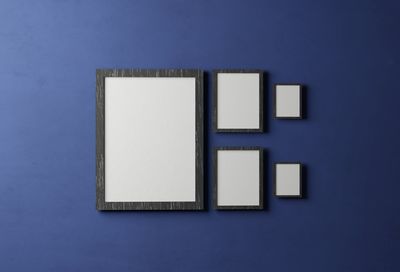 White rectangular vertical frame composition hanging on a blue wall 