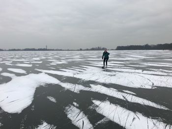 Woman skating on ice rink against sky