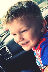 Tilt shot of smiling boy sitting in car