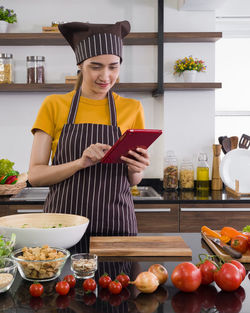 Full length of woman holding food in kitchen
