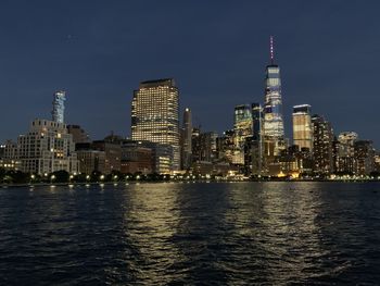 River by illuminated buildings against sky at night