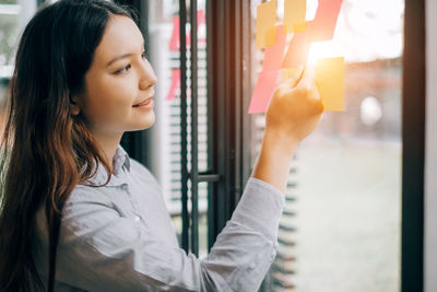 Portrait of young woman looking through window