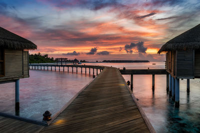 Pier over sea against sky during sunset