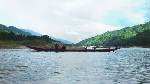 Scenic view of river by mountains against sky