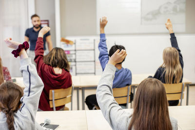 Children raising hands in classroom