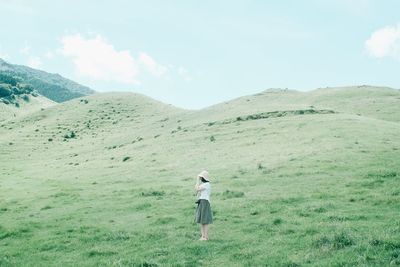 Rear view of man standing on field against sky