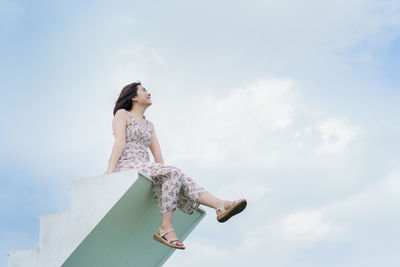 Low angle view of woman looking away against sky