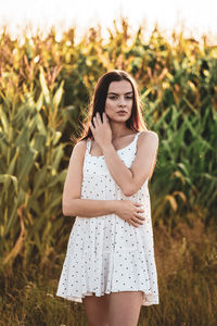 Portrait of young woman standing against plants