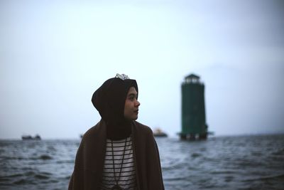 Young man looking at sea against sky