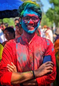 Portrait of young man in holi color with mobile phone outdoors