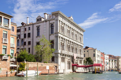 Buildings by canal against sky in city