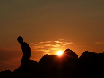 Silhouette man walking on hill against sky during sunset