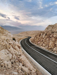 Empty road with with dividing line. rocky terrain, beautiful sky.