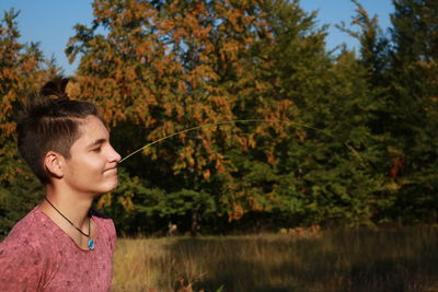 Young teenage boy holding hey straw in his mouth in the forest