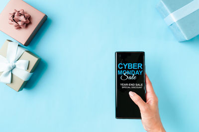 Low angle view of hand holding text against blue background