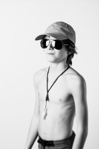 Shirtless boy wearing sunglasses standing against white background