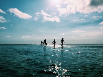 Silhouette children playing in sea against sky