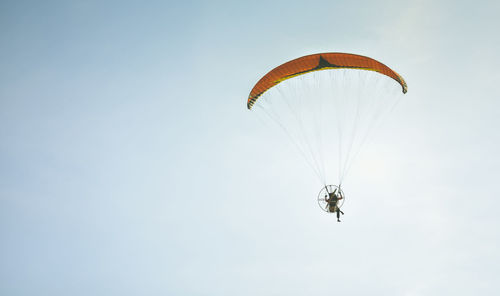 Low angle view of person paragliding against sky