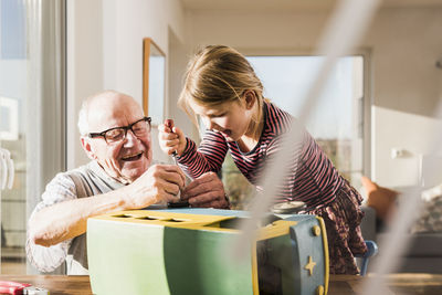 Grandfather and granddaughter assembling toy bus