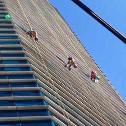 Low angle view of people on steps against clear blue sky
