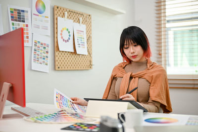 Portrait of young woman using laptop while sitting on table