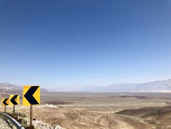 Road sign against clear blue sky