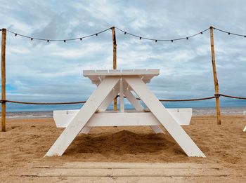 Lifeguard hut on beach against cloudy sky