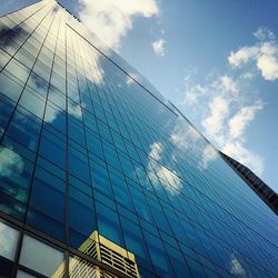 Low angle view of modern building against cloudy sky