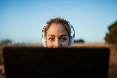 Portrait of young woman using smart phone against sky