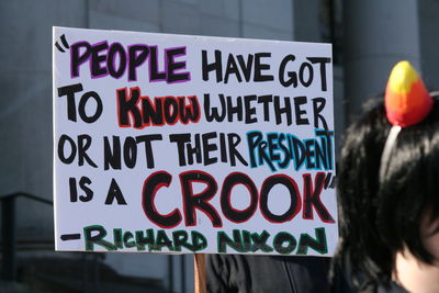 Cropped image of man holding sign with text