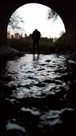 Silhouette of man standing in tunnel