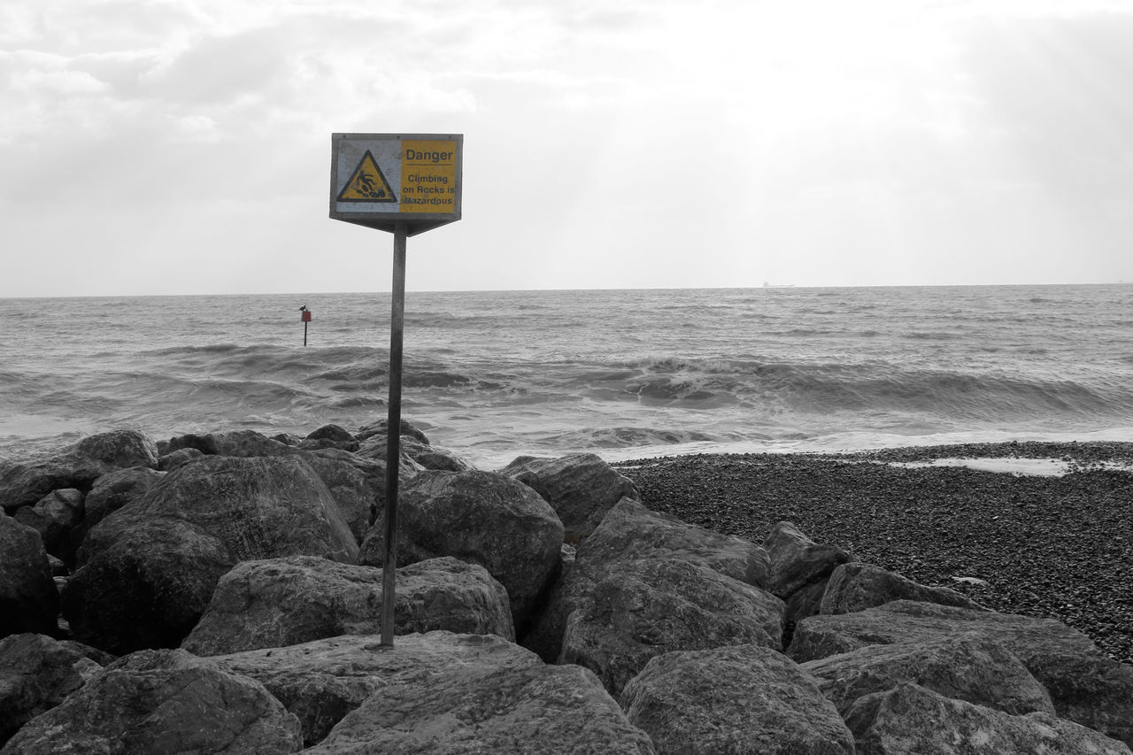 SIGN ON BEACH AGAINST SKY