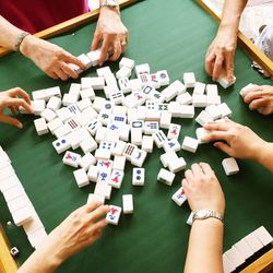 High angle view of people playing with mahjong tiles on table