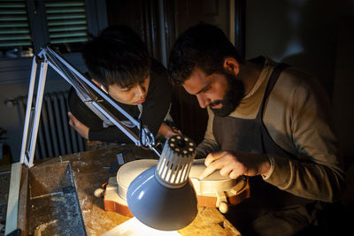 Pair of craftsmen violin maker while working on a new violin in the workshop