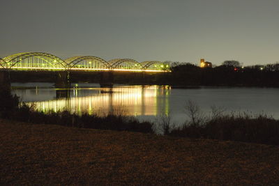 Illuminated bridge over river against sky at night