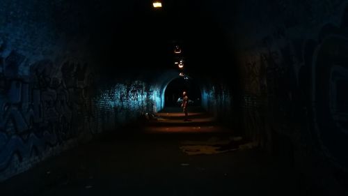 Illuminated tunnel amidst buildings at night