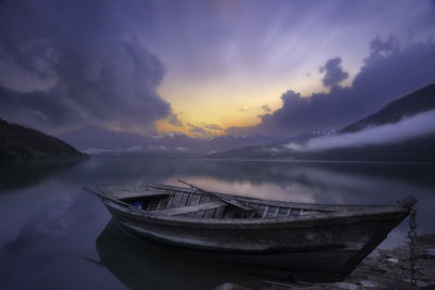 Boat moored in sea against sky during sunset