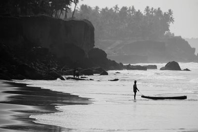 Man on rocks at shore against sky