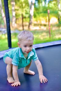 Portrait of cute boy sitting on field, trampoline 2 yars boy