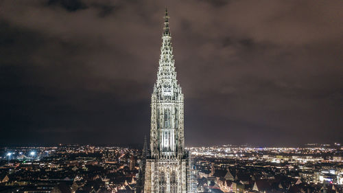 Communications tower in city against sky at night