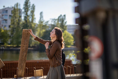 Side view of young woman looking away while standing outdoors