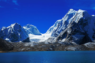 Scenic view of snowcapped mountains against blue sky