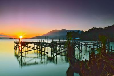 Pier on sea against sky during sunset
