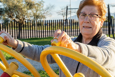 Elderly woman practices sport moving the wheels in a bio-healthy park, at sunset